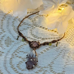 Close up of raw amethyst pendant with macrame cage and bronze details
